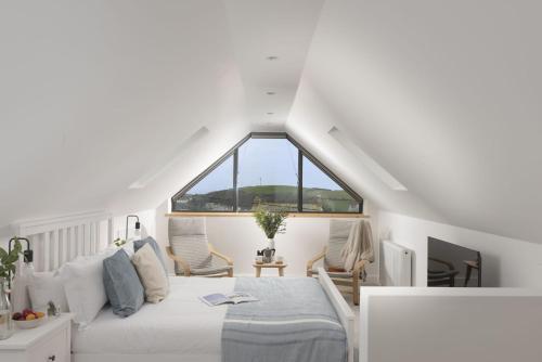 a bedroom with a white bed and a large window at Atlantic Point, Porthleven in Porthleven