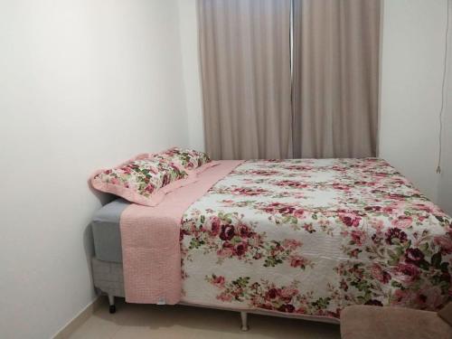 a bedroom with a bed with a floral comforter and pillows at Apartamento com otima localizacao em Itajai SC in Itajaí
