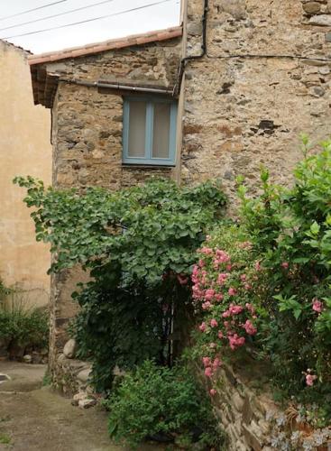 a stone building with a window and some flowers at Une tiny house dans le coeur d'un ancien village. in Roquebrun