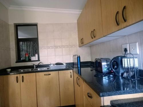 a kitchen with wooden cabinets and a black counter top at 7 on school - Cozy guesthouse 15 min drive from airport and close to major highways in Germiston