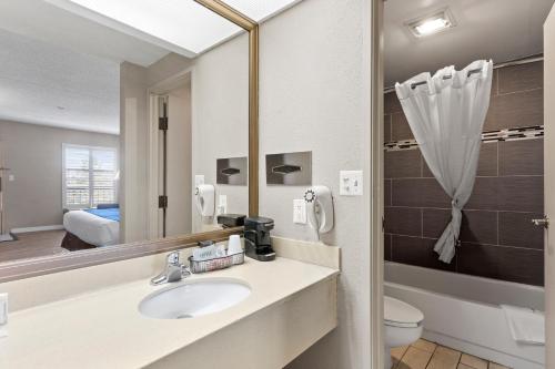 a bathroom with a sink and a toilet and a mirror at Travelodge by Wyndham Pueblo in Pueblo