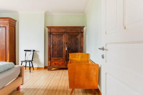 a room with a wooden cabinet and a chair at Beautiful mansion with swimming pool and jacuzzi in Bilzen
