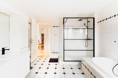 een witte badkamer met een bad en een douche bij Beautiful mansion with swimming pool in Bilzen