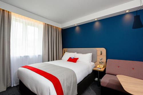 a hotel room with a large bed and a chair at Holiday Inn Express Canterbury by IHG in Canterbury