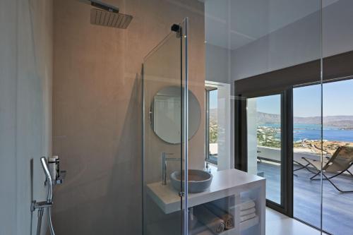 a bathroom with a shower with a sink and a mirror at Elounda Black Pearl Villa in Agios Nikolaos