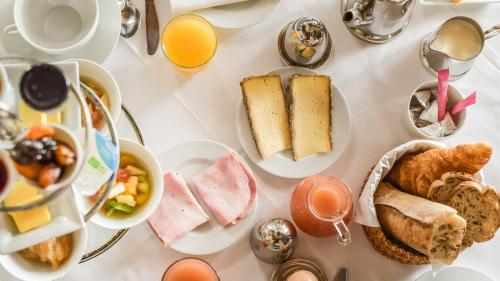 Hôtel la Maison de Rhodes & Spa في تروي: طاولة بيضاء مليئة بأطباق طعام الإفطار