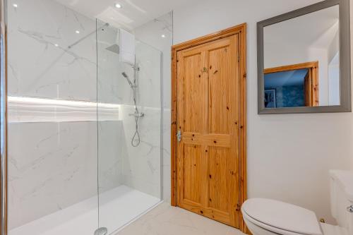 a bathroom with a shower and a toilet and a wooden door at Little Treasure in Whitby