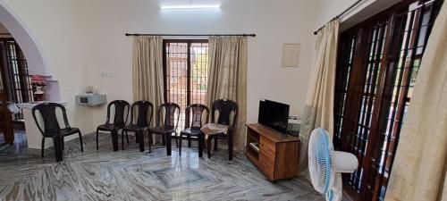 a dining room with chairs and a table and a television at Sea View Homestay in Mangalore