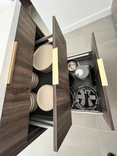 une cuisine avec des placards en bois, des assiettes et des casseroles dans l'établissement Refuge En Ville - Appart Cosy avec Garage, à Annecy