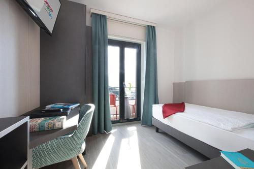 a bedroom with a bed and a desk and a window at Hotel Geranio Au Lac in Locarno