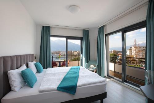 ロカルノにあるホテル グラニオ オー ラックのベッドと大きな窓が備わるホテルルームです。