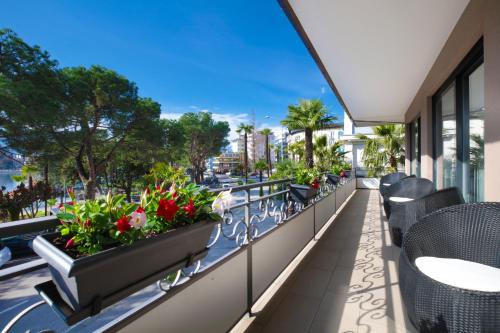 einen Balkon mit Stühlen und Blumen auf einem Gebäude in der Unterkunft Hotel Geranio Au Lac in Locarno