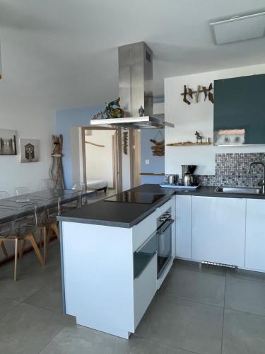 une cuisine avec des armoires blanches et une table à l'intérieur dans l'établissement Les Toits de Moriani, à San-Nicolao