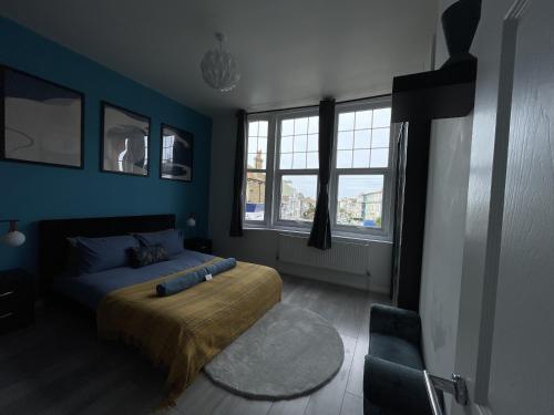a bedroom with a bed with blue walls and windows at Modern Sea View Apartment in Margate
