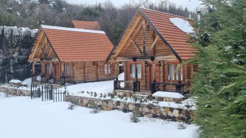 a log cabin in the snow with snow on the ground at Wood Hills Hotel & Resort in Mayrūbā