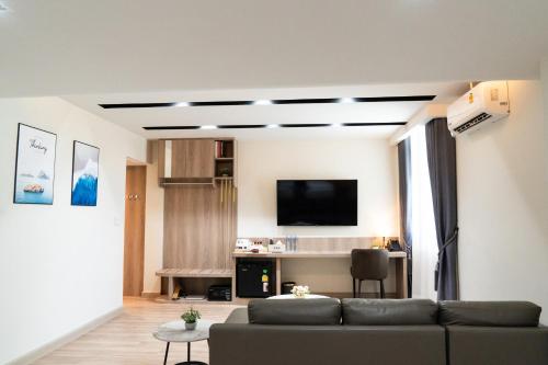 a living room with a couch and a tv at indigo Hotel Hatyai in Ban Kohong