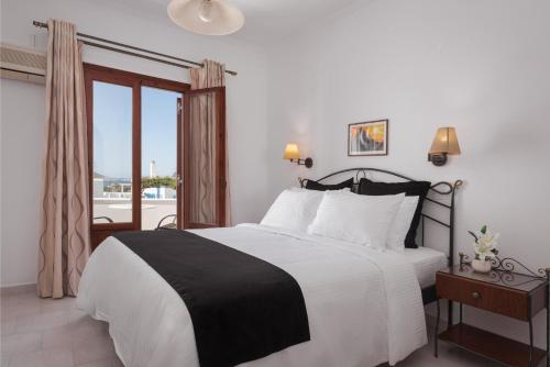 a bedroom with a black and white bed and a balcony at Sunset Paros Naousa in Naousa
