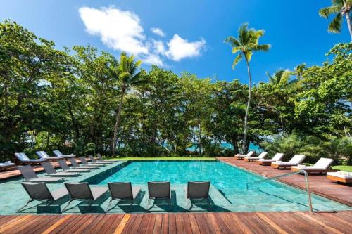 una piscina con tumbonas y palmeras en Casa 3A Tivoli Ecoresidences, en Praia do Forte