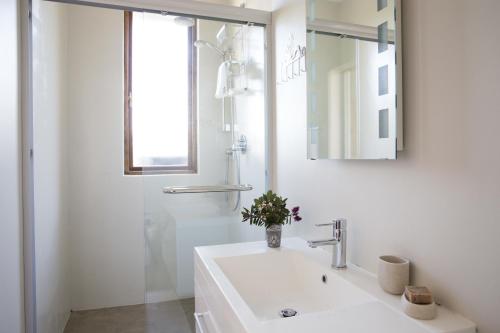 a white bathroom with a sink and a mirror at 43 On Sandstone in Somerset West