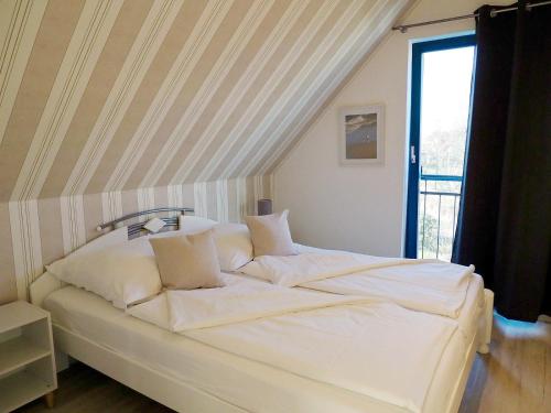een groot wit bed in een kamer met een raam bij Meeresrauschen 1 in Groß Kirr