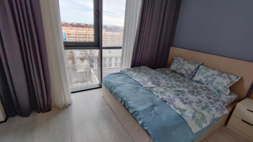 1 dormitorio con cama y ventana grande en ЖК Akay city. Новый ремонт en Tashkent