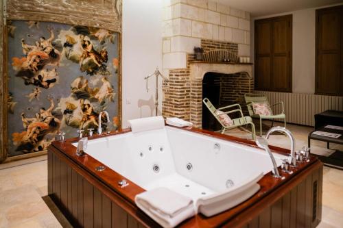 a bath tub in a room with a fireplace at Le Champ des Oiseaux & Spa in Troyes