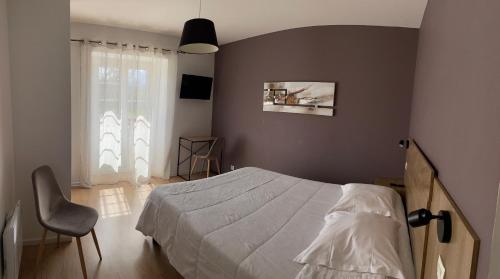 a bedroom with a bed and a chair and a window at Hotel Mendy in Saint-Jean-le-Vieux