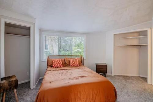 ein orangefarbenes Bett in einem Zimmer mit Fenster in der Unterkunft Groovy Getaway Centrally Located in Augusta