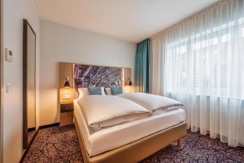 a bedroom with a bed and a large window at CityClass Hotel Alter Markt in Cologne