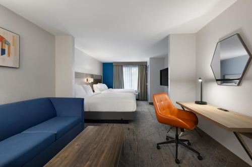 a hotel room with a blue couch and a bed at Holiday Inn Express Savannah Airport by IHG in Savannah