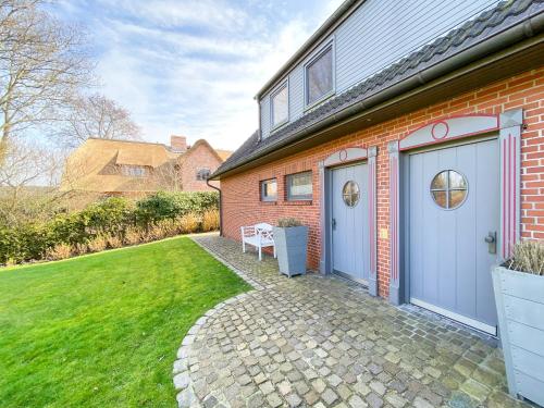 a brick house with two garage doors and a lawn at Lee Biberhüs in Archsum