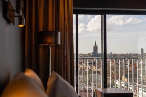 una camera d'albergo con finestra affacciata sulla città di Hampshire Hotel - Delft Centre a Delft