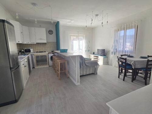 a kitchen with white cabinets and a table with chairs at Chez Choucas Maison e Maisonette - Goelba in Portoferraio
