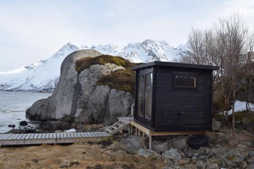 a black tiny house on the shore of a body of water at Nydelig hytte med fantastisk beliggenhet ved sjøen in Laupstad