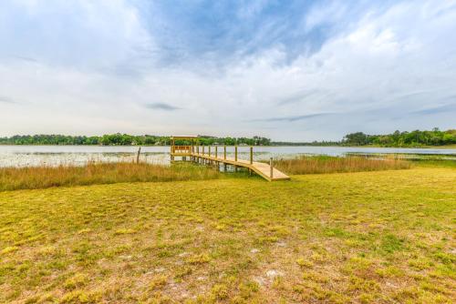 a dock in a field next to a body of water at Lakefront Keystone Heights Cottage with Private Dock in Keystone Heights