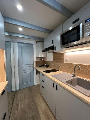 une cuisine avec des armoires blanches et un évier dans l'établissement Sky, à Corbeil-Essonnes