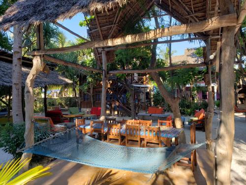 a hammock in a resort with tables and chairs at Sagando Bungalows Zanzibar in Michamvi