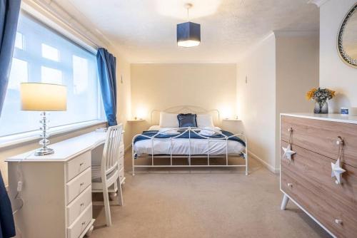 a bedroom with a bed and a desk and a window at 4 The Sandlings in Aldeburgh