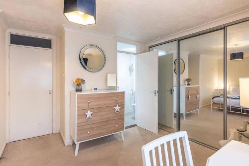 uma sala com um quarto com um espelho e uma cómoda em 4 The Sandlings em Aldeburgh
