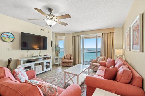 a living room with two red chairs and a flat screen tv at Bahama Sands PH3 - Oceanfront - Crescent Beach Section in Myrtle Beach