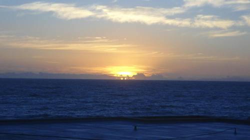 a sunset over the ocean with a ship in the distance at Sunseaker- Beachfront Complex in Ballito