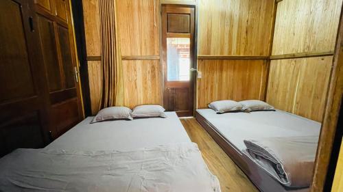 two beds in a room with wooden walls at Homestay Yến Long in Lạng Sơn