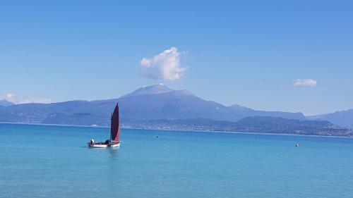 a sail boat in the water with a mountain in the background at B&B Villa Giulia in Desenzano del Garda