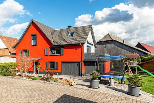 ein orangenes Haus mit einem Spielplatz davor in der Unterkunft Ferienhaus Sieger in Salem