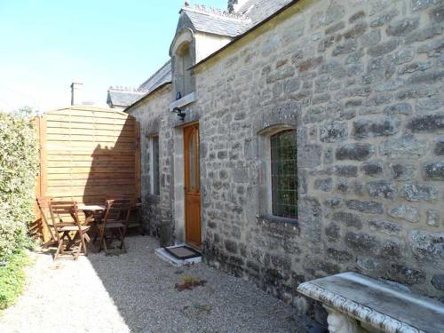 - un bâtiment en pierre avec une table et des chaises à l'extérieur dans l'établissement La Creullinnerie Bis, à Morville