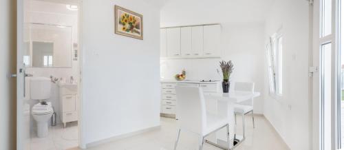 a white kitchen with a white table and chairs at Villa Lilin San in Donji Humac
