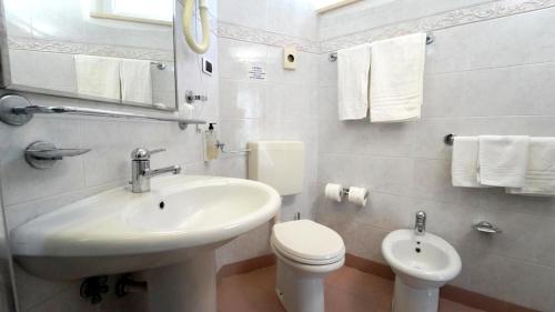 La salle de bains blanche est pourvue d'un lavabo et de toilettes. dans l'établissement Hotel King, à Alba Adriatica