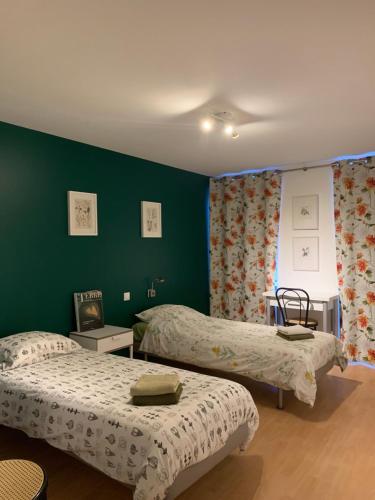 2 camas en una habitación con paredes verdes en A MARIE ET GABRIEL, en L'Ile-Bouchard