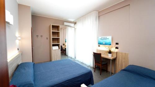 アルバ・アドリアティカにあるHotel Kingのベッド2台、デスク、テーブルが備わる客室です。
