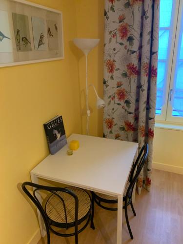 a white table and chairs in a room with a window at A MARIE ET GABRIEL in L'Ile-Bouchard